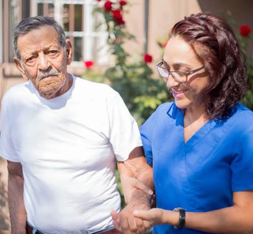 EnCasa Care patient walking with a cane and being supported by a caregiver