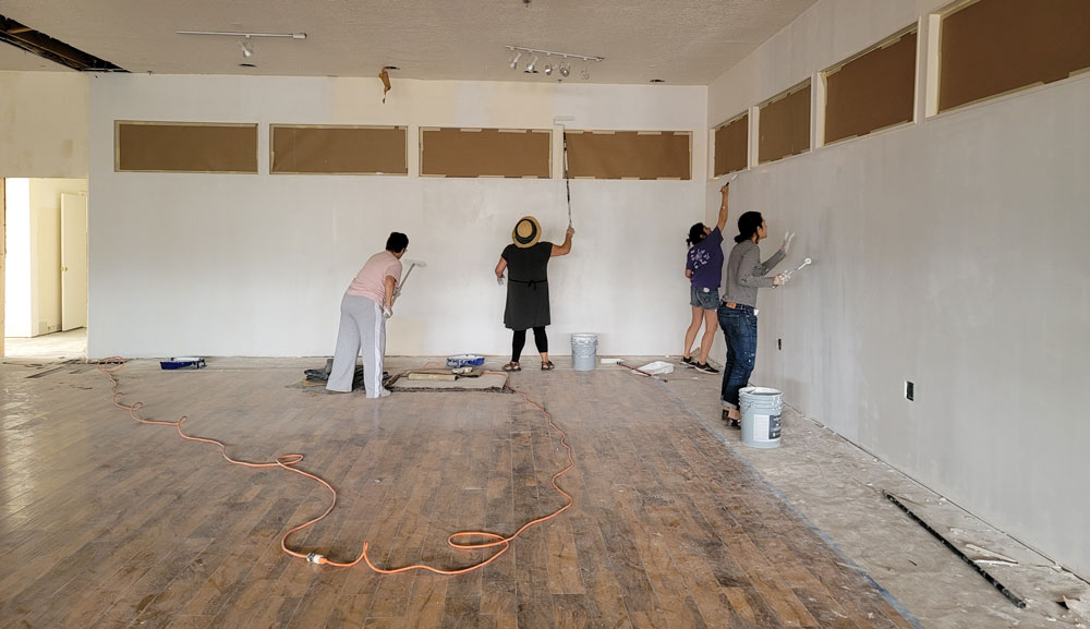 Four Encuentro team members painting interior walls in the new building