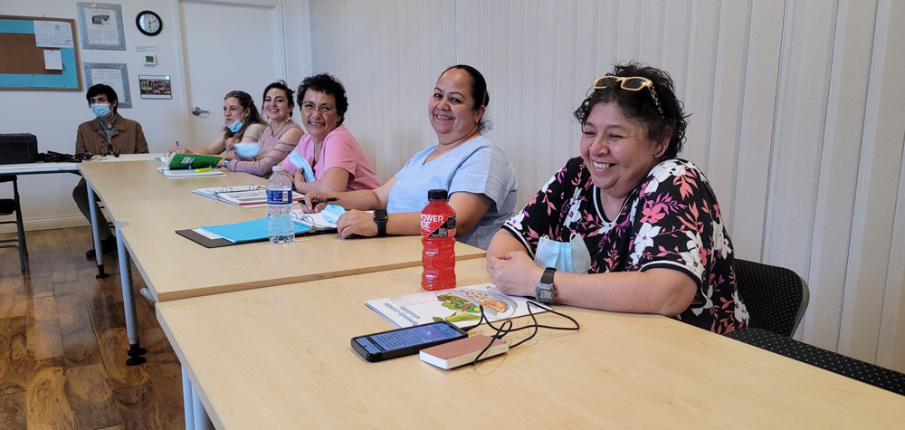 Martha Hurtado and other community members sitting together at a table in the Encuentro space